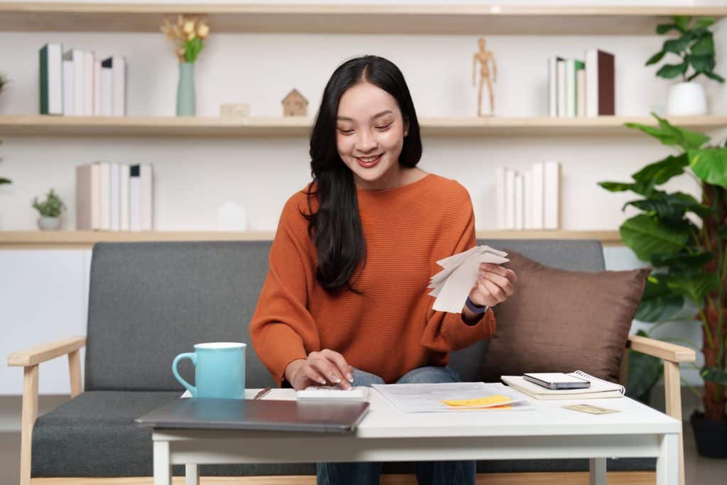 A cheerful woman sorts through tax paperwork at home, embodying a positive approach to tax preparation.