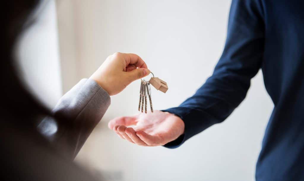 eine Hand übergibt einer anderen Hand den Schlüssel einer Wohnung