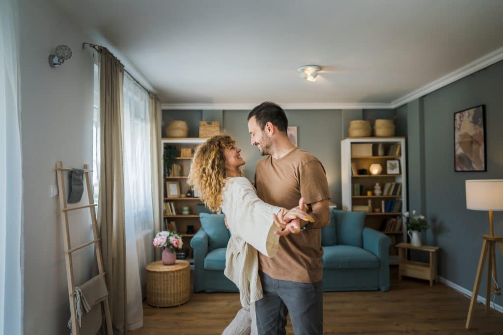 Ein glückliches Paar – ein erwachsener Mann und eine Frau, Ehemann und Ehefrau – tanzen in ihrem neuen Zuhause